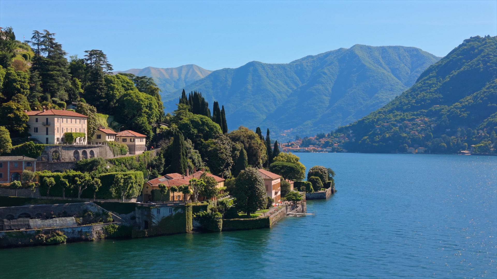 Villas and gardens on the shore of Lake Como beneath green mountains
