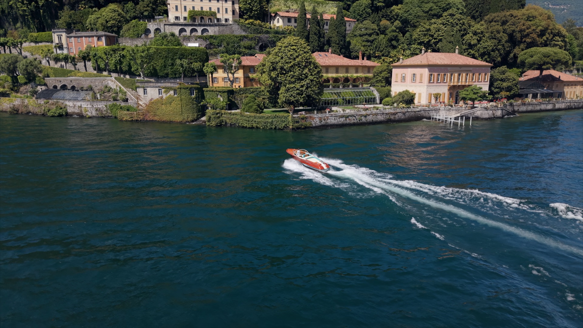 Riva boat passing villas and terraced gardens on Lake Como
