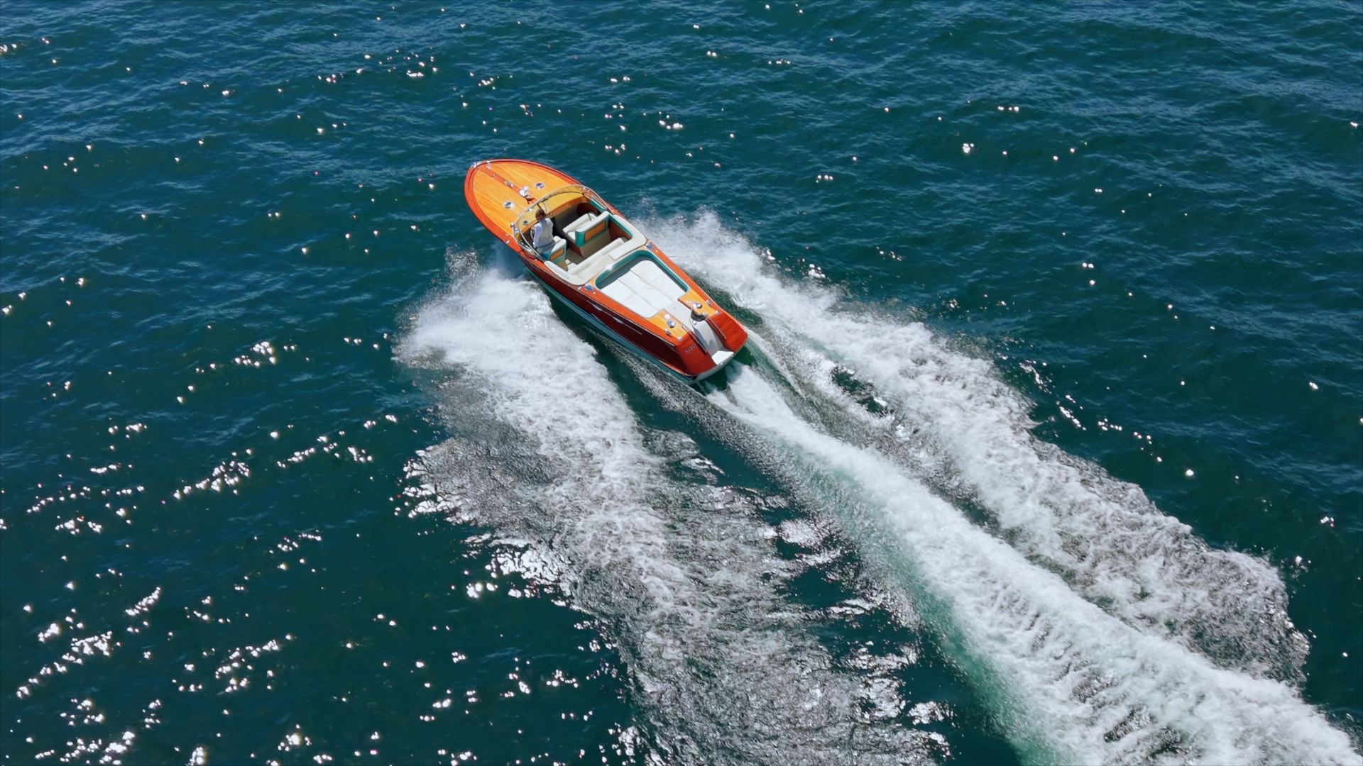 Riva boat crossing Lake Como, seen from above with its broad white wake