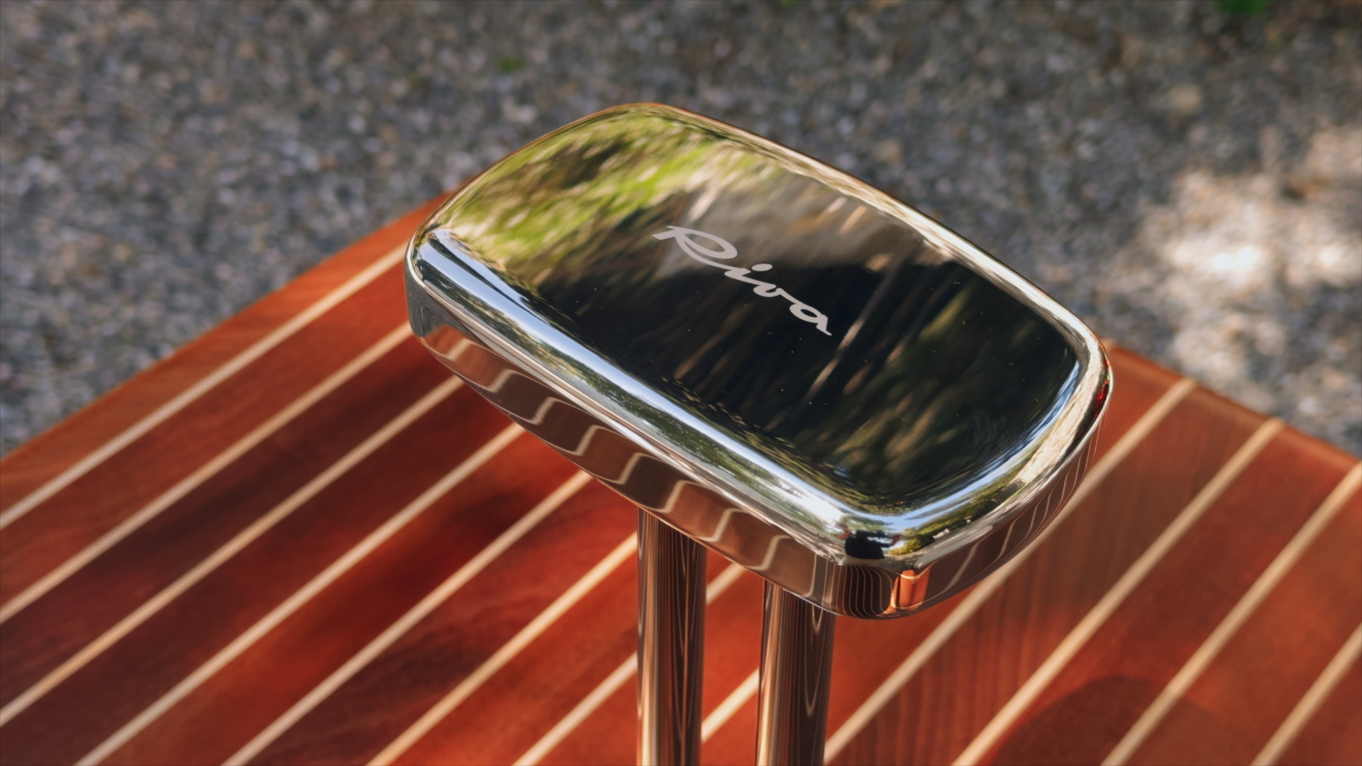 Chrome detail with Riva lettering on striped wood in Massimo Castagna’s Exteta × Riva collection